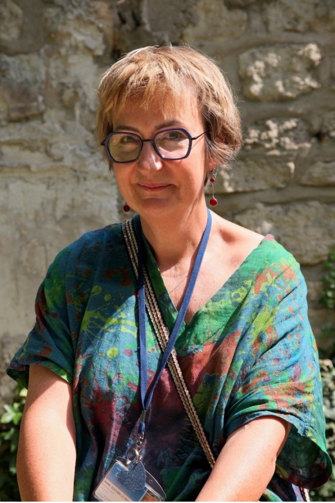 Photographie d'Anne-Solenn, psychologique. Elle est dehors, au soleil, et sourit