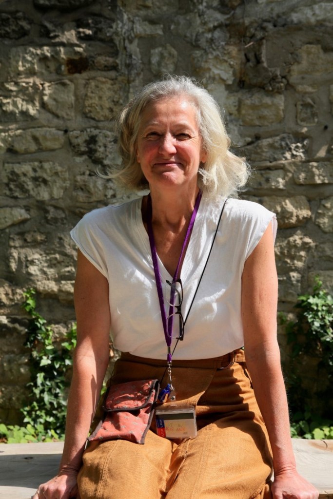 Photographie de Véronique, assistante sociale. Elle est dehors, au soleil, et sourit